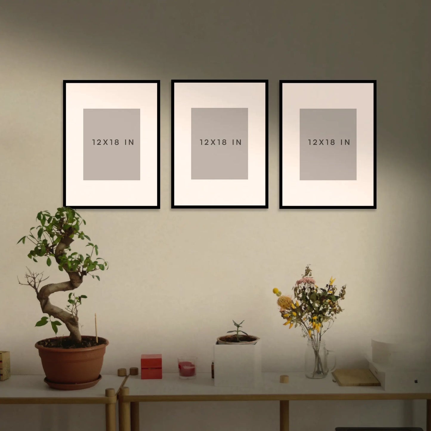 Three framed with size guide on a wall above a table with decorative items.