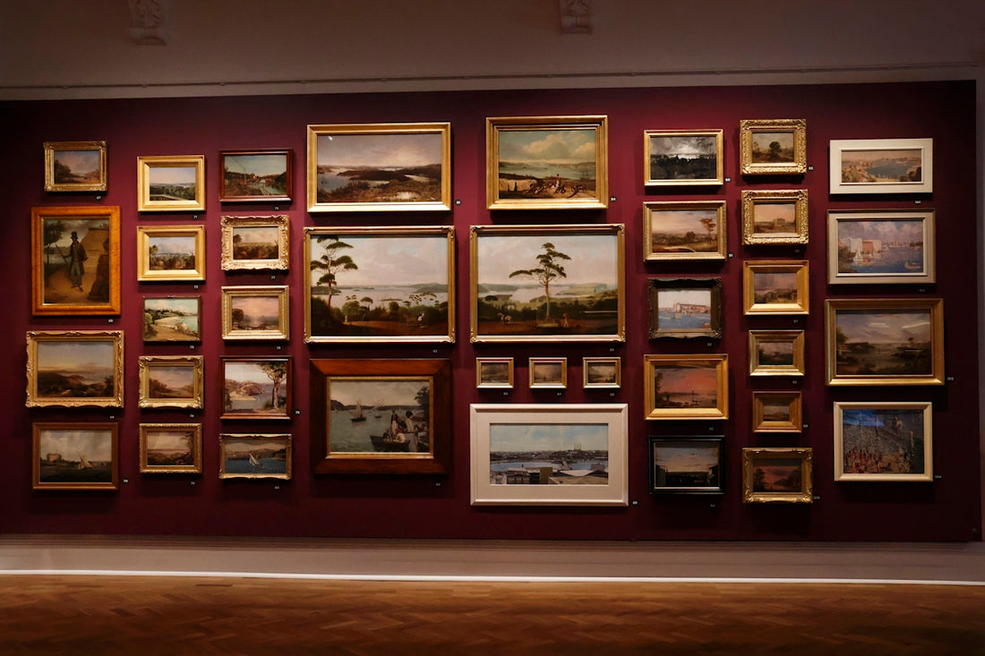 Collection of landscape paintings displayed on a wall.