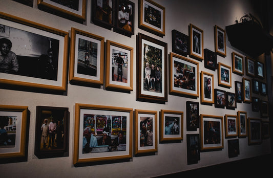 Numerous framed photographs hanging on a gallery wall.