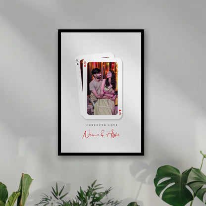 A framed custom playing card wall art print hanging on wall. custom photo of a couple inside a playing card design, with a King of Spades card layered behind queen, Framiqa.