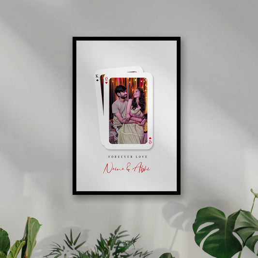 A framed custom playing card wall art print hanging on wall. custom photo of a couple inside a playing card design, with a King of Spades card layered behind queen, Framiqa.