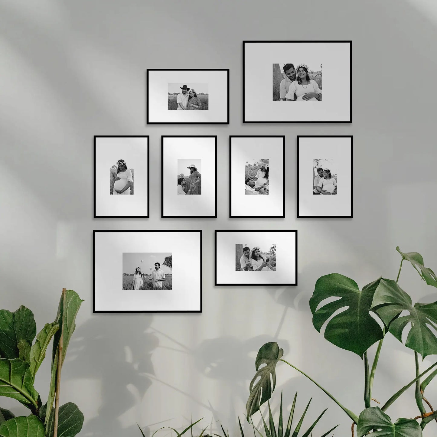 Wall with framed black and white photos and green plants. Framiqa Gallery Wall Set